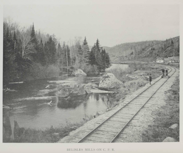Trois hommes sur la voie ferrée, au bord de la Rivière-du-nord, dans la campagne à proximité du village de Val-David. Un des hommes est debout au bord de la voie ferrée, les deux autres sur un petit wagonnet qui sert à l’entretien des voies.