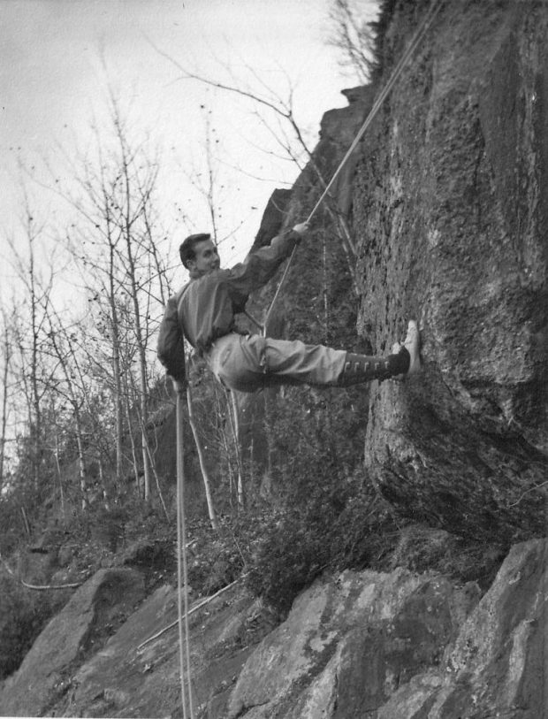 Un grimpeur sur une paroi rocheuse, retenu par une double corde.