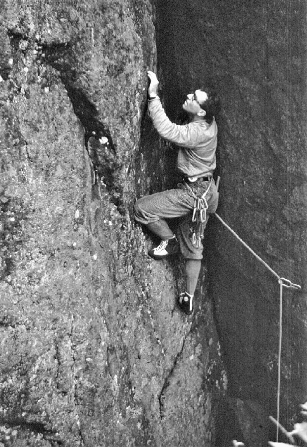 Un grimpeur sur une paroi rocheuse tenant une corde.