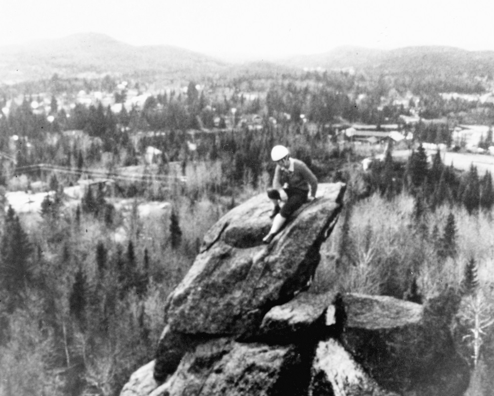 Une femme au sommet d’un rocher. Au loin derrière la campagne autour de Val-David.