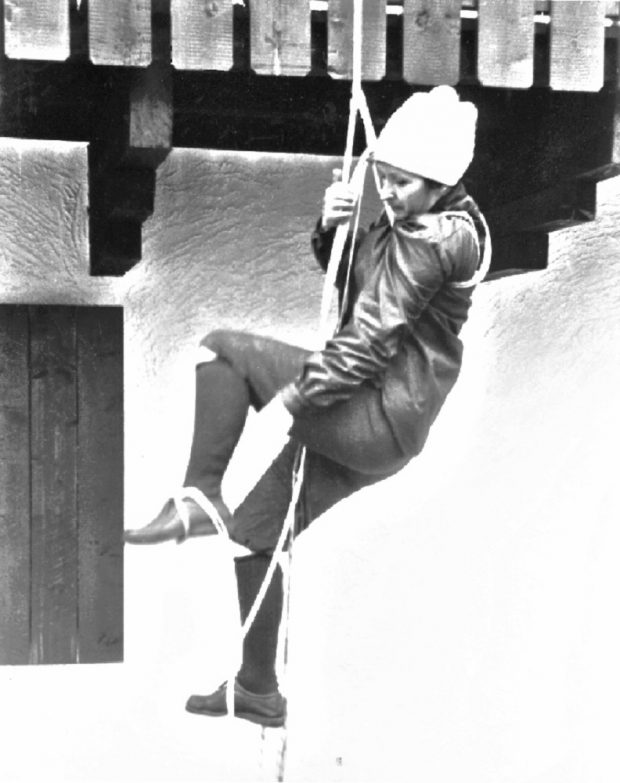 Une jeune femme grimpe une corde accrochée à une poutre de l’Auberge le Rouet à Val-David.