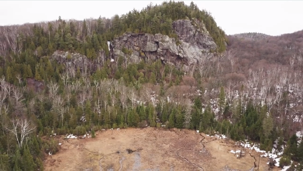 Plan éloigné d’une montagne, ses arbres et ses parois rocheuses bien visibles.