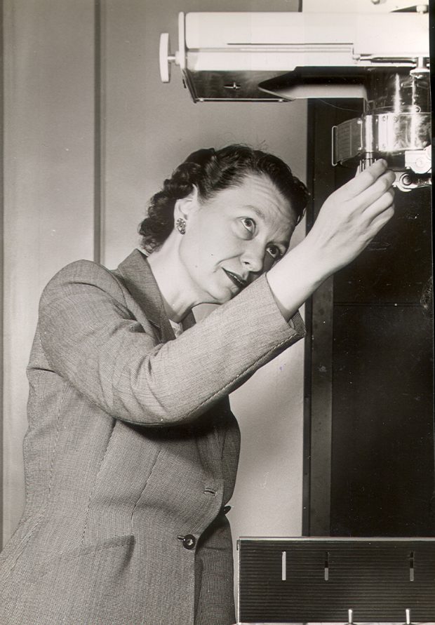 Photo en noir et blanc d’une femme en tailleur ajustant un appareil médical.