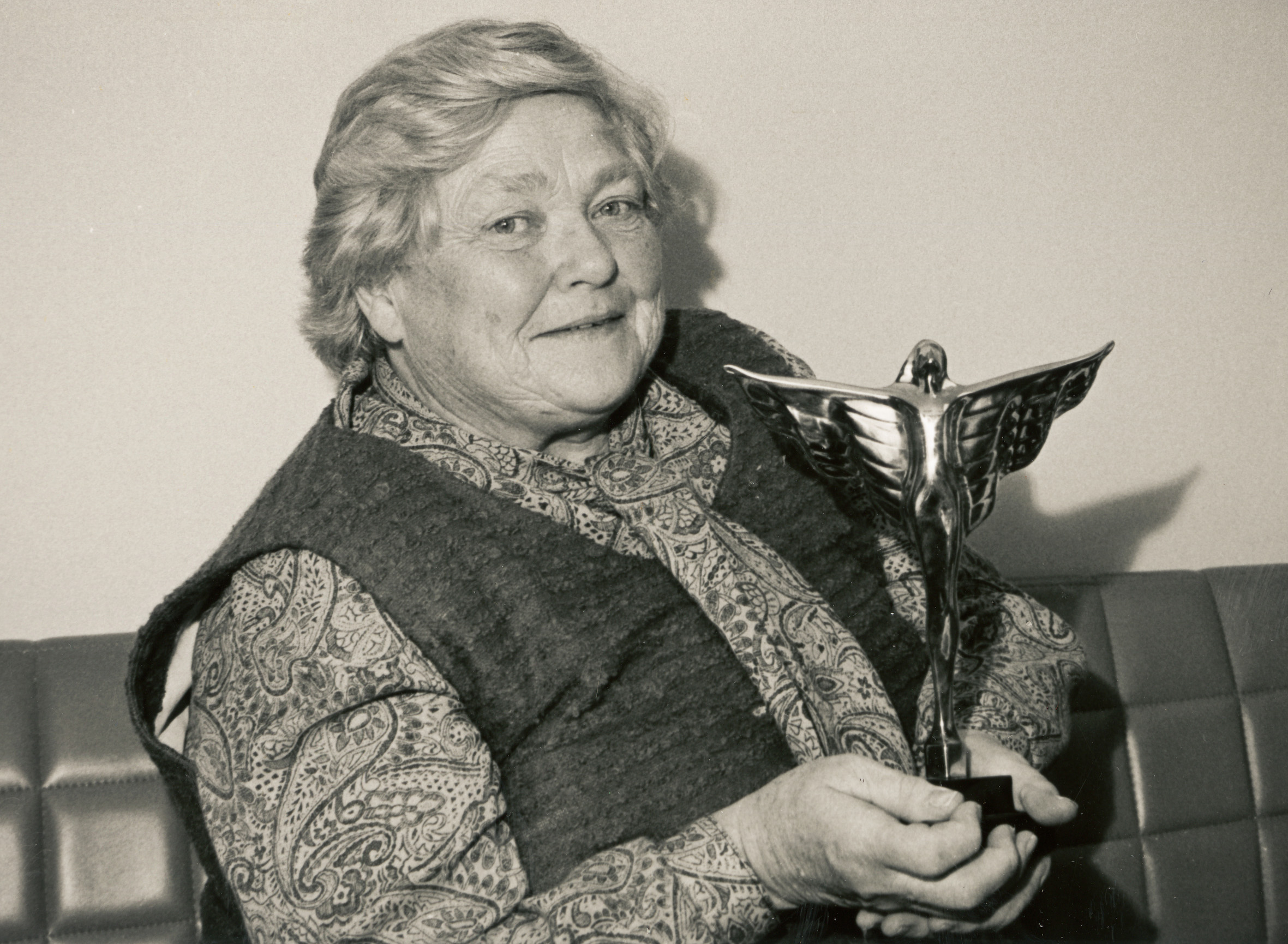 Une femme brandit un trophée en souriant.