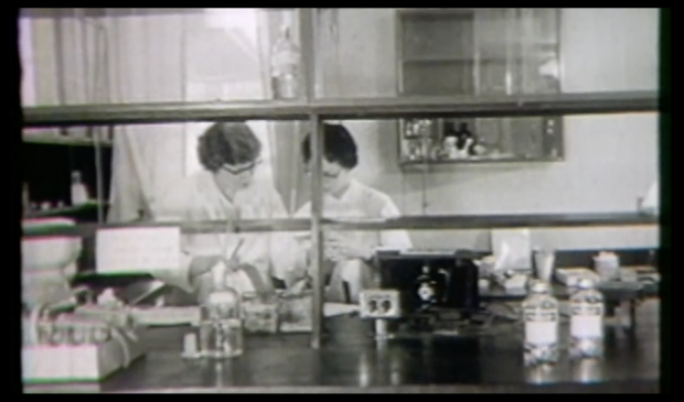 Image d’une vidéo en noir et blanc où deux femmes travaillent dans le laboratoire.