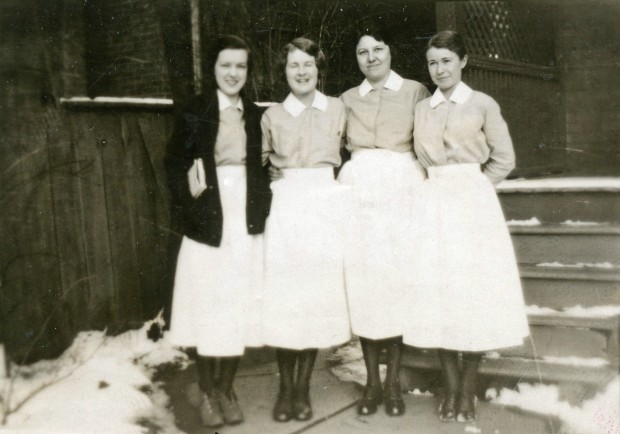 Quatre femmes souriantes portent de longues jupes blanches et des chemisiers légers.