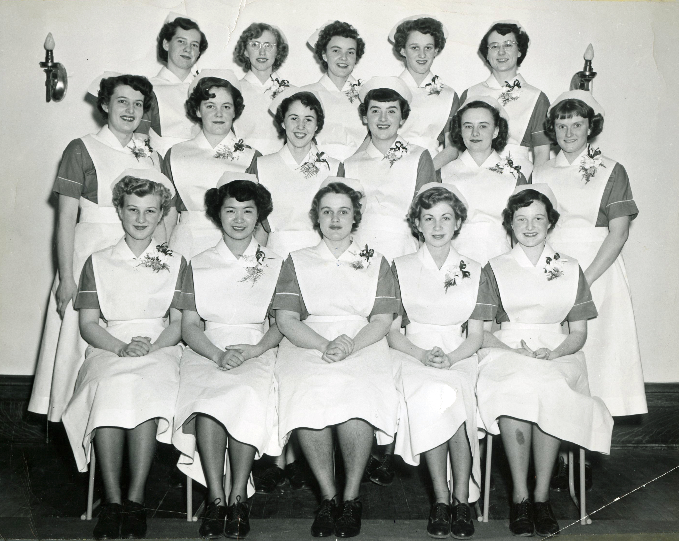 Seize femmes souriantes en uniforme d’infirmière assises ou debout pour une photo officielle.