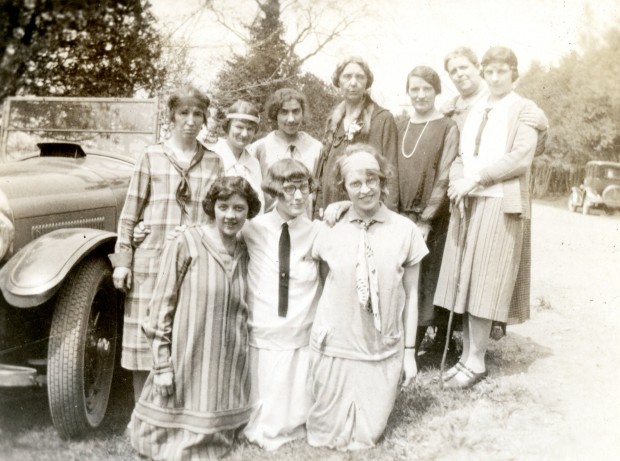 Dix femmes habillées de façon décontractée posent à côté d’un véhicule motorisé un jour ensoleillé. Il y a des arbres à l’arrière-plan.