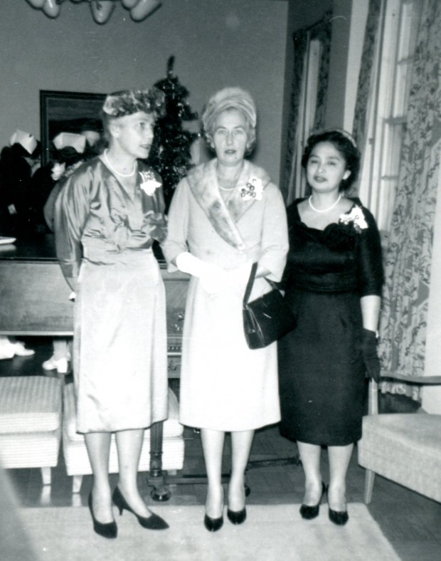Trois femmes posent pour l’appareil photo. Elles sont habillées de façon élégante et portent un corsage.
