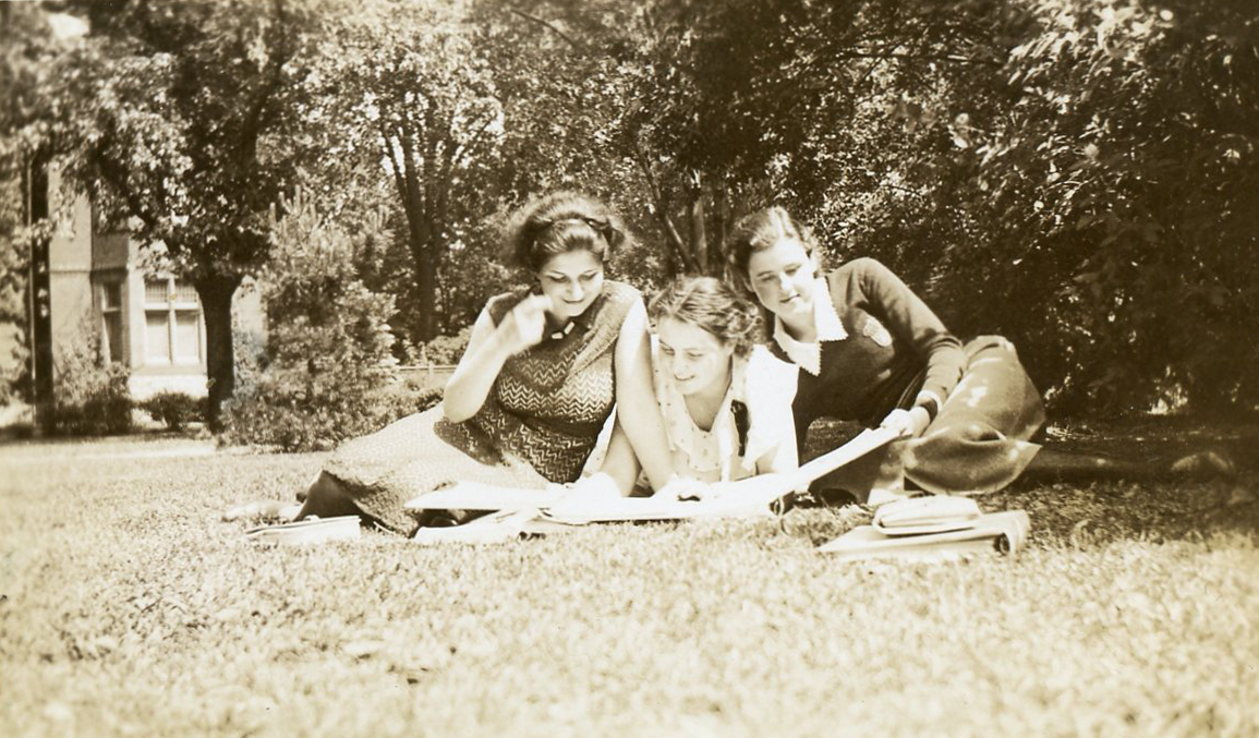 Trois jeunes femmes habillées de façon décontractée étudient dans un parc.