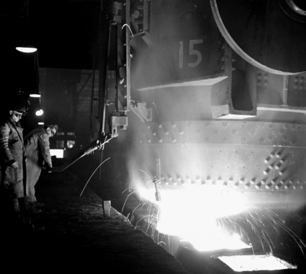 Deux ouvriers dans une aciérie versant de l’acier en fusion
