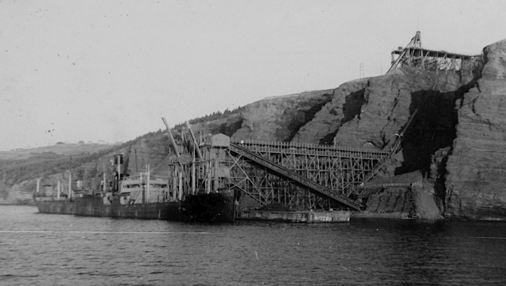 Vieille photo d’un navire marchant amarré à un quai de chargement avec un tapis roulant