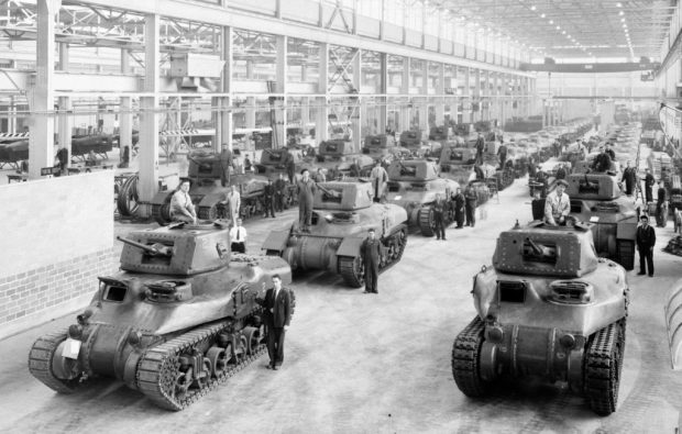 Trois rangées de dizaines de chars d’assaut et des ouvriers dans une usine