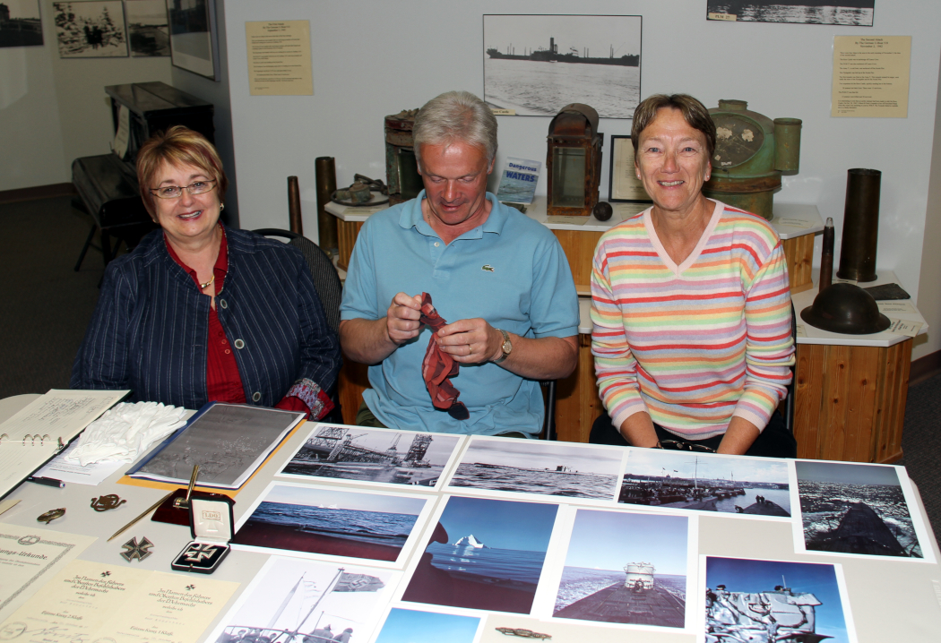 trois personnes assises à une table couverte de photos