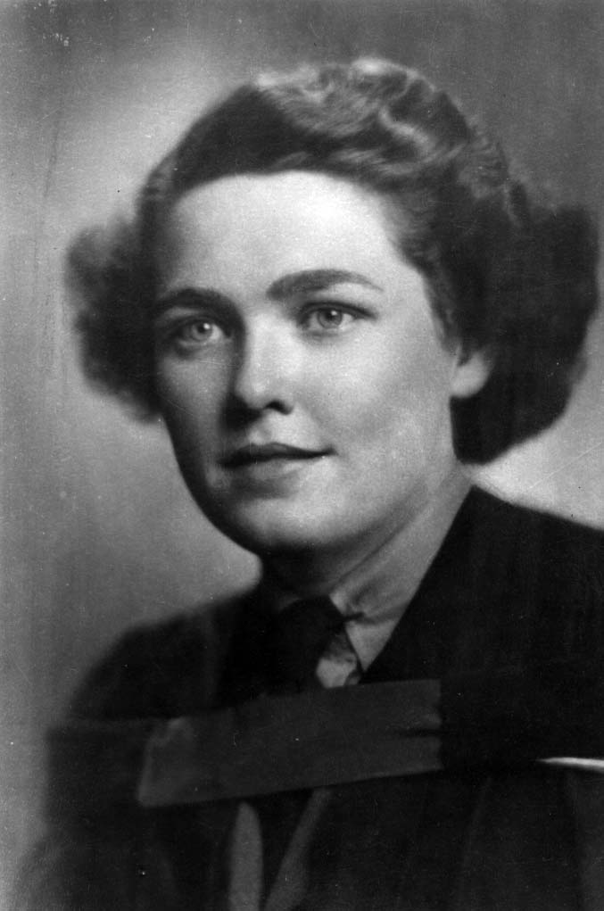 Portrait noir et blanc d’une femme aux cheveux courts ondulés en tenue formelle.