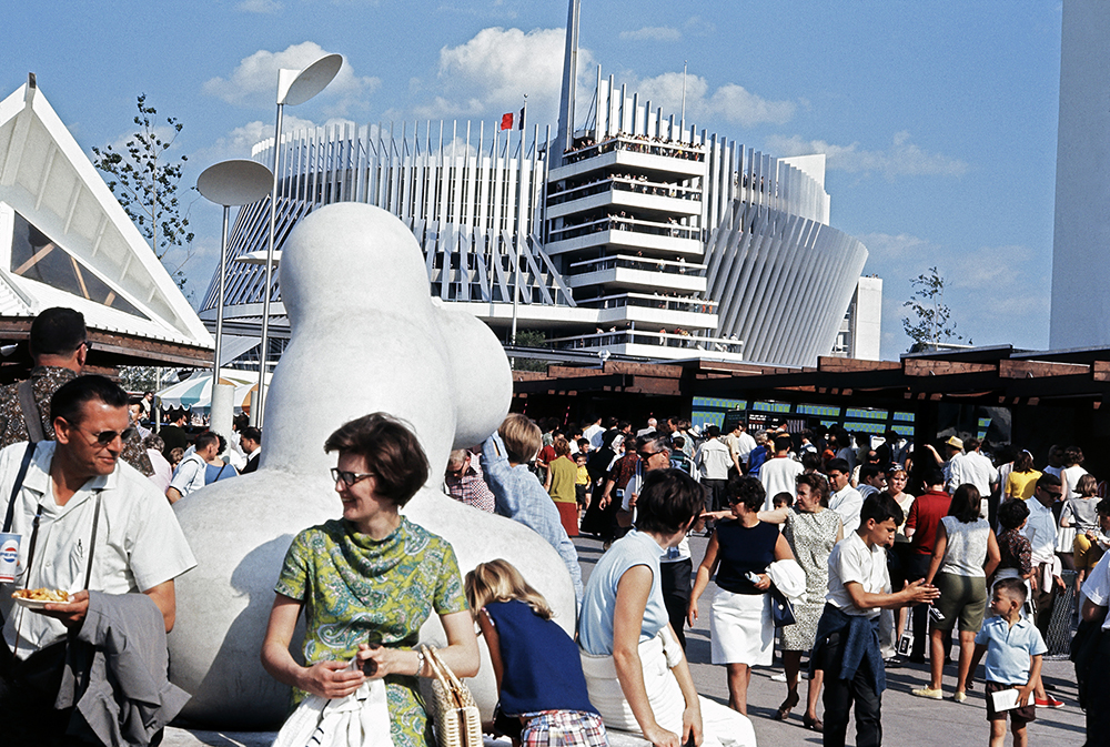 Lors d’Expo 67, une foule se trouve à proximité du pavillon de la France, un bâtiment circulaire blanc à plusieurs niveaux, aujourd’hui devenu le Casino de Montréal.