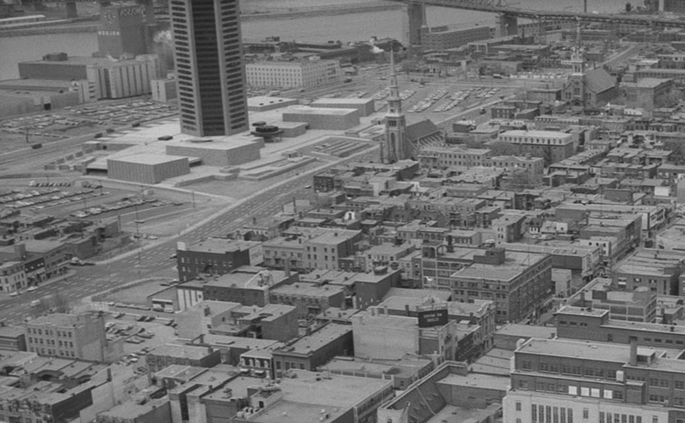 En noir et blanc, la tour d’environ 25 étages de l’ancienne maison de Radio-Canada s’impose sur le boulevard René-Lévesque Est. À proximité, la brasserie Molson se dresse, avec sa façade décorée d’une horloge, sur les rives du fleuve Saint-Laurent.