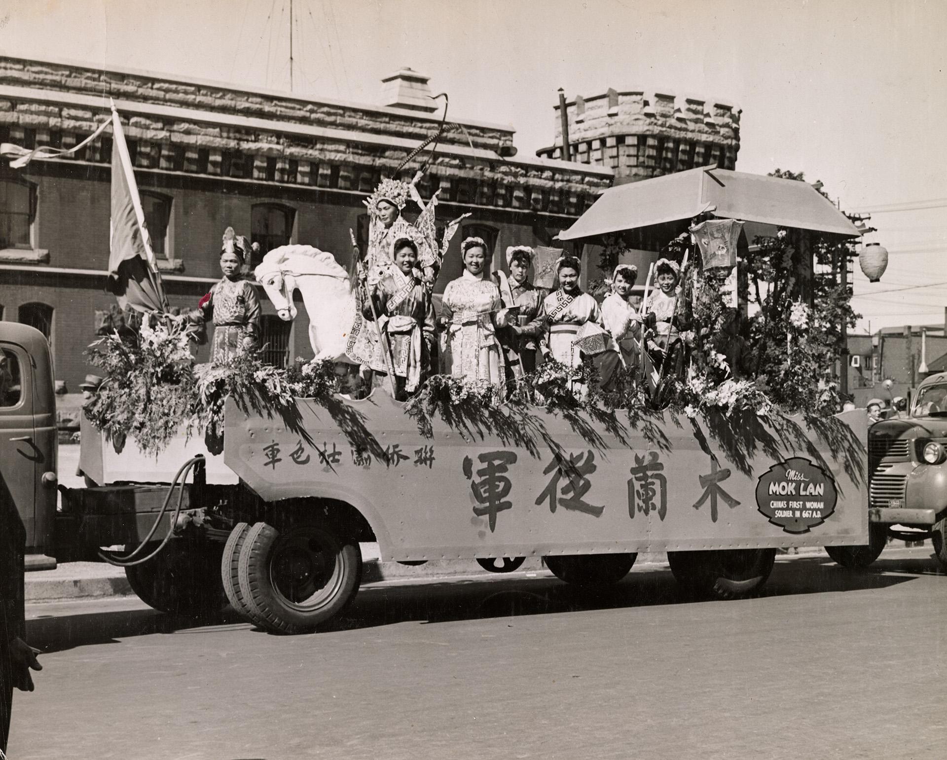 <span style="font-weight: 400;">Un char de parade mettant en scène des artistes de l’opéra </span><i>Mulan rejoint l’armée</i><span style="font-weight: 400;">. Six guerrières en costume se tiennent debout, armes à la main, tandis qu’un guerrier est assis sur un cheval décoratif.</span>