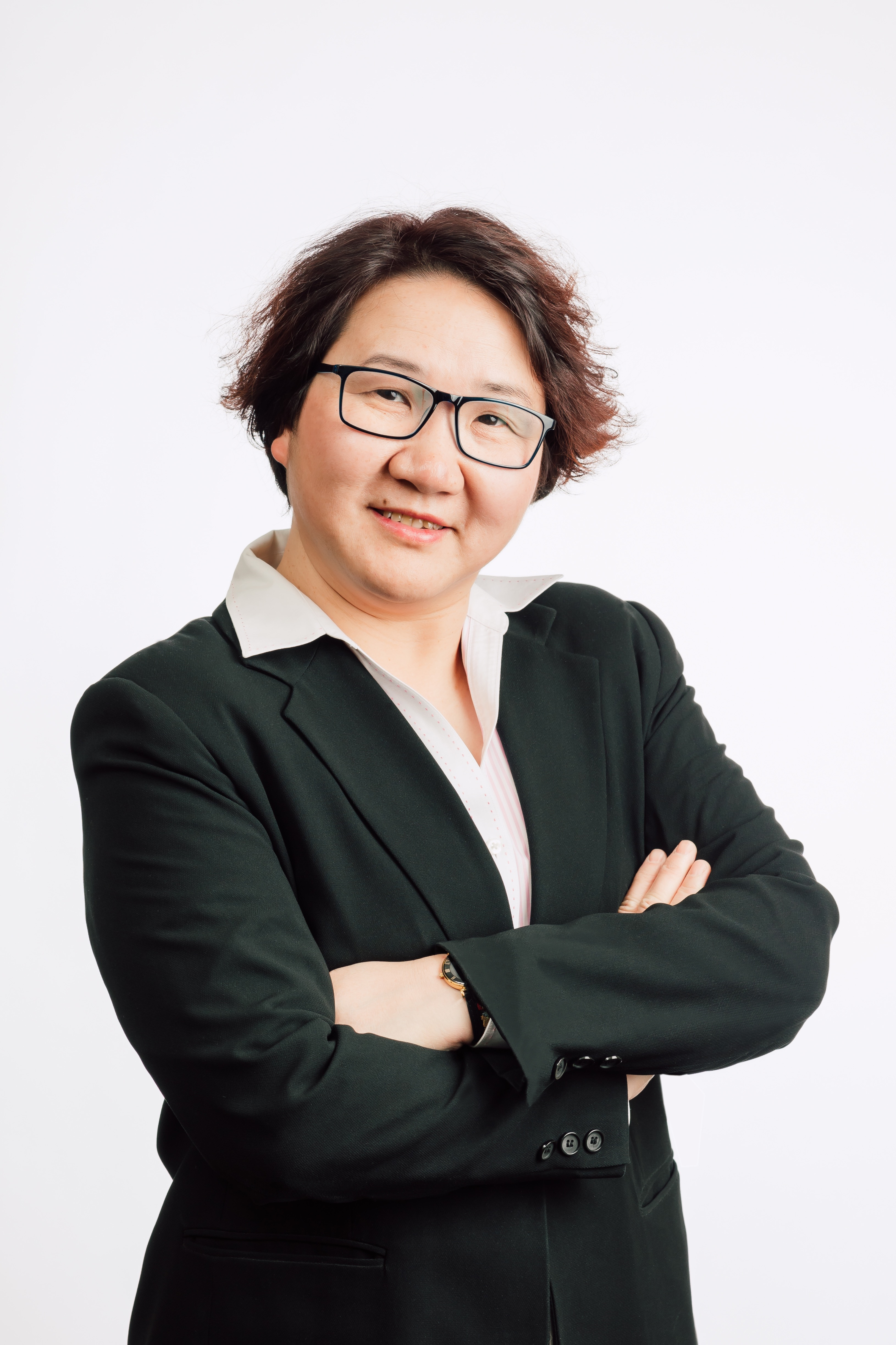 <span style="font-weight: 400;">Portrait d’Alice Chan debout sur un fond blanc. Ses cheveux courts sont séparés sur le côté et elle porte des lunettes et un blazer noirs.</span>