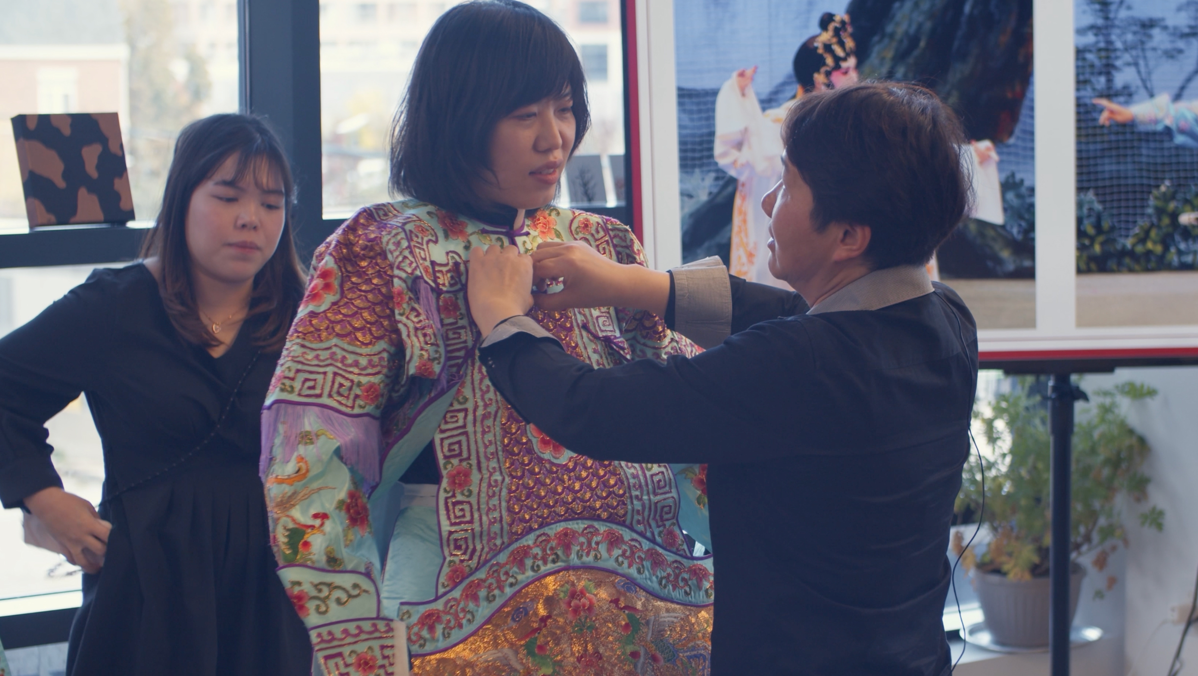 <span style="font-weight: 400;">Alice Chan aide une personne participant à l’atelier à enfiler un costume d’opéra chinois.</span>