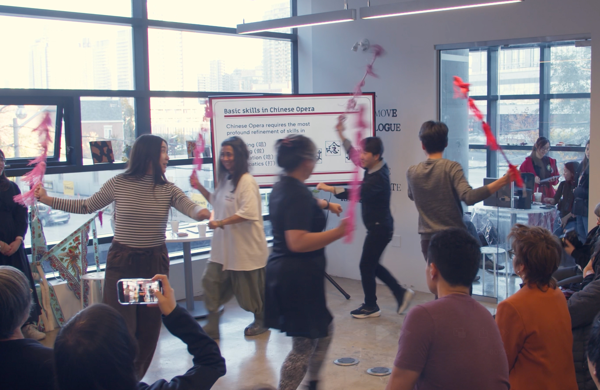 <span style="font-weight: 400;">Workshop participants trot in a circle with decorated sticks that they wave in the air.</span>