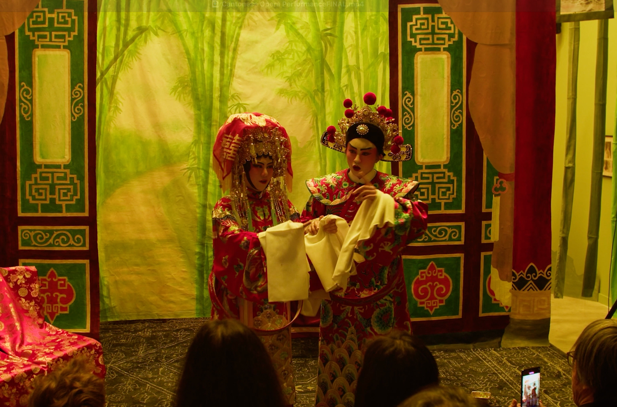 <span style="font-weight: 400;">Deux artistes d’opéra cantonais, incarnant respectivement un rôle masculin et un rôle féminin, apparaissent dans des costumes élaborés et majestueux, avec des coiffes somptueuses, lors d’une mini-représentation sur la scène de </span><i><span style="font-weight: 400;">Parfum des foudres</span></i><span style="font-weight: 400;">.</span>