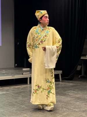<span style="font-weight: 400;">Un interprète vêtu d’un costume jaune pâle aux détails discrets se tient dans une pose calme et pensive.</span>
