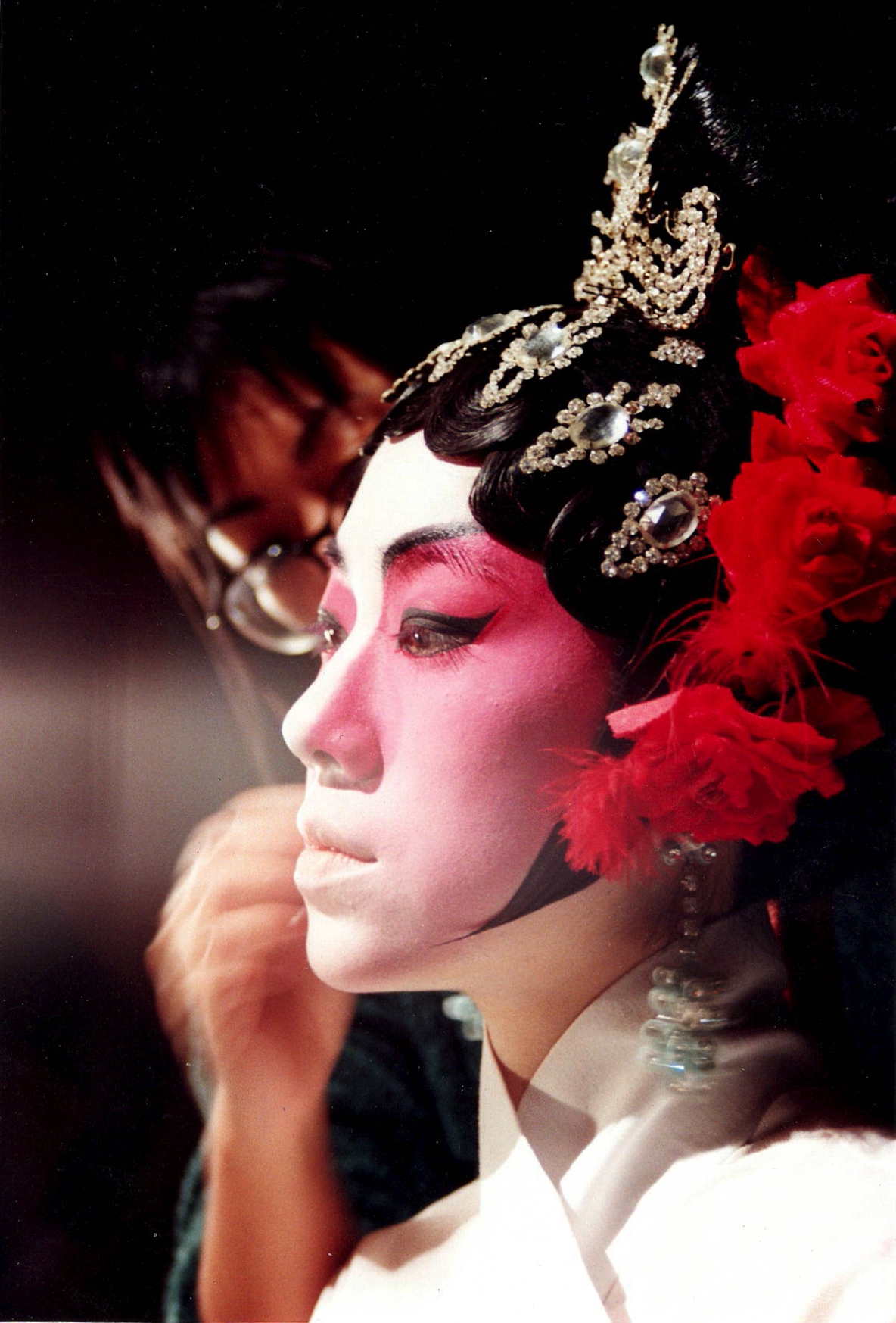 <span style="font-weight: 400;">Gros plan sur le profil d’une actrice, tandis qu’une femme lui applique du maquillage sur le visage, mettant en valeur les détails complexes et les expressions concentrées.</span>