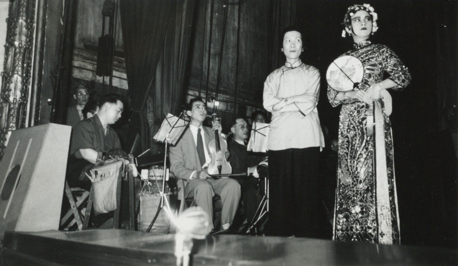 <span style="font-weight: 400;">Audience view of musicians playing at the corner of the stage with two actresses mid-scene next to them.</span>