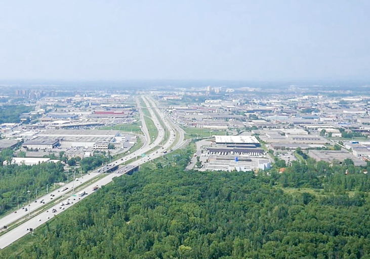 Photographie aérienne en couleur. Vue sur l’autoroute Jean-Noël Lavoie et le secteur industriel de Laval.