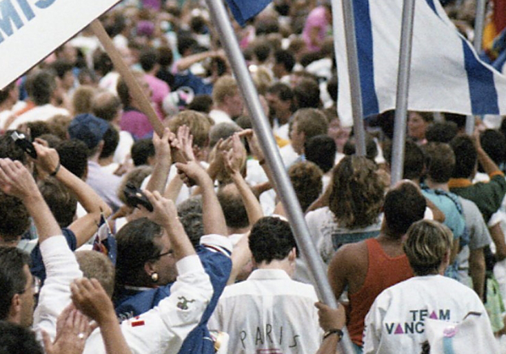 Des foules d'athlètes et d'autres participants, agitant divers drapeaux nationaux lors de la cérémonie d'ouverture de la célébration 90.