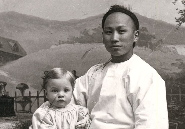 Employé de maison chinois posant pour un photographe, assis sur une chaise avec un jeune enfant sur le genou droit