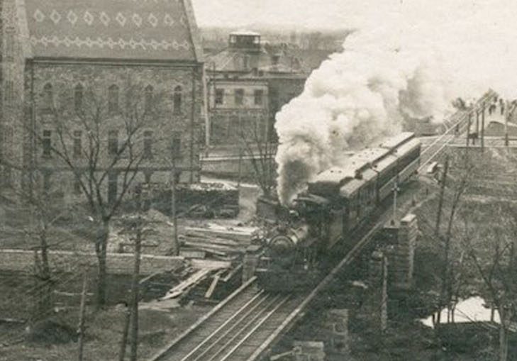 Photographie montrant un train circulant sur la voie ferrée et l’hôtel de ville d’Almonte à l’arrière-plan, années 1950