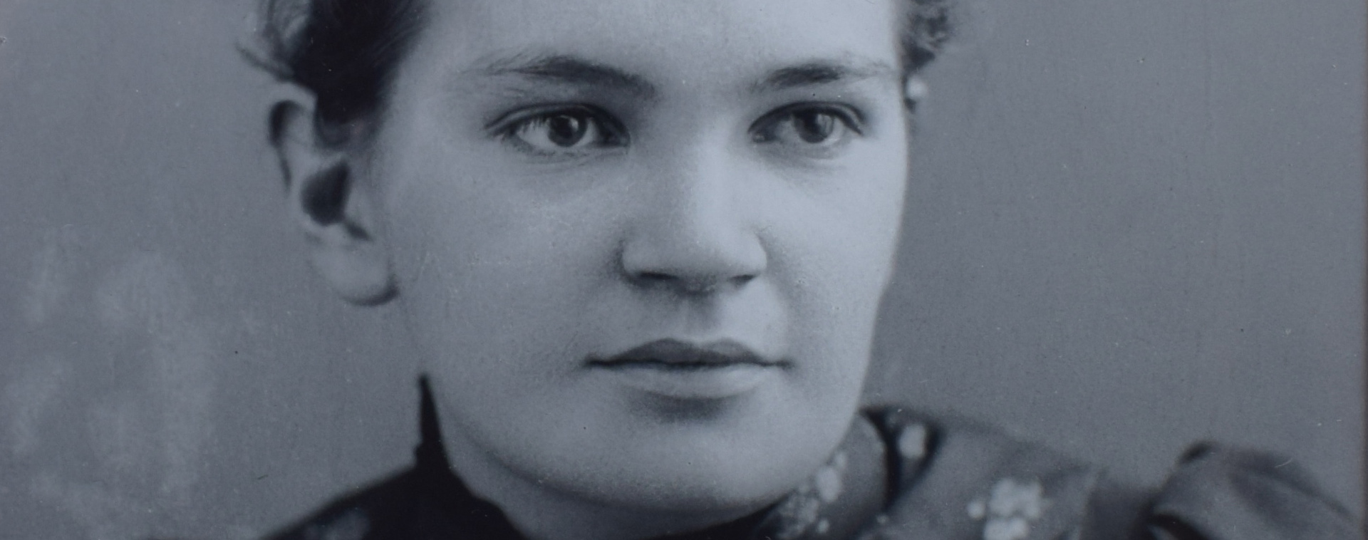 Photographie montrant le visage de la docteure Maude Elizabeth Abbott en gros plan panoramique. Elle est jeune et porte une robe à fleur. Son regard est perçant. Elle sourit paisiblement. Elle a 22 ans.