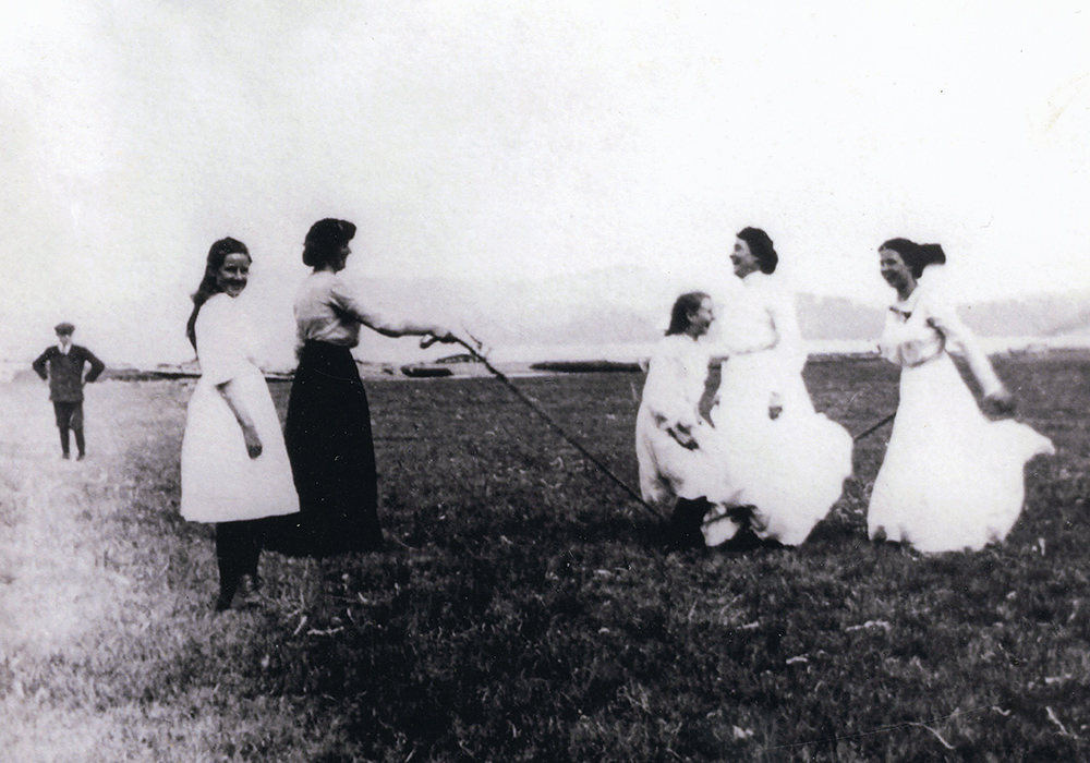 Une photographie noir et blanc des femmes jouent à la corde à sauter dans un camp.