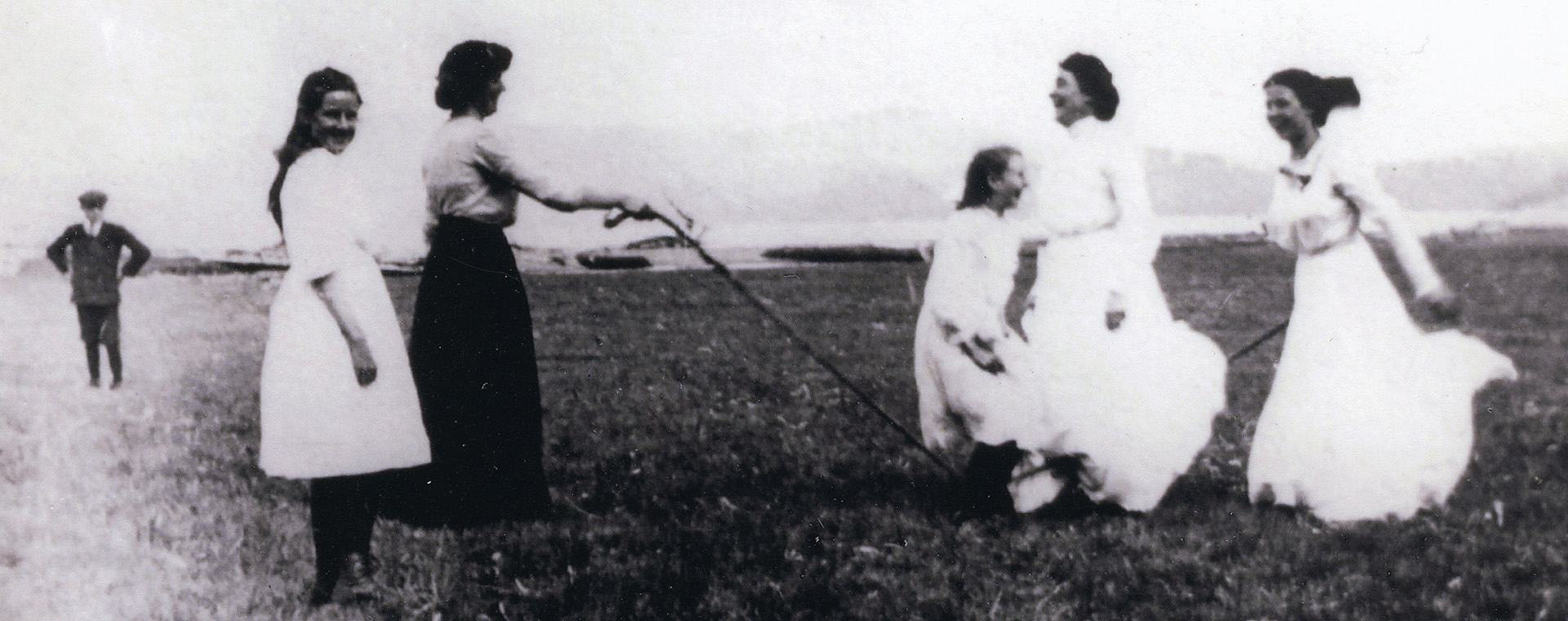 Une photographie noir et blanc des femmes jouent à la corde à sauter dans un camp.