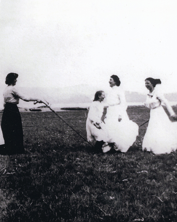 Une photographie noir et blanc des femmes jouent à la corde à sauter dans un camp.