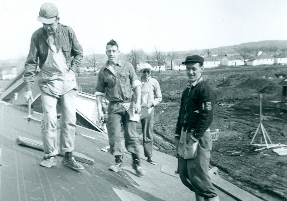 Photo noir et blanc d'un groupe de quatre hommes sur un toit.