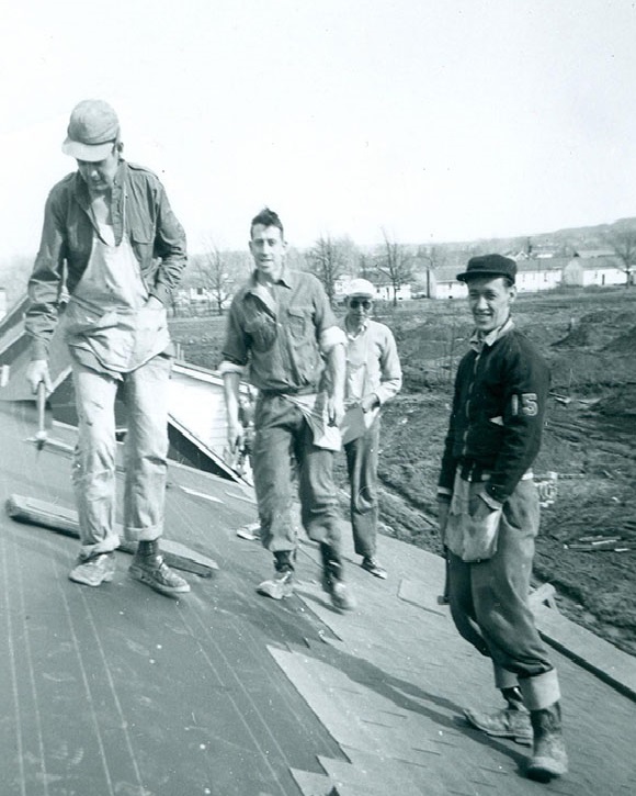 Photo noir et blanc d'un groupe de quatre hommes sur un toit.