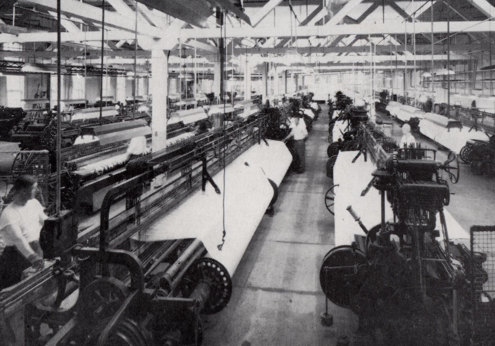 Un sol d'usine avec plusieurs rangées de machines à tisser.