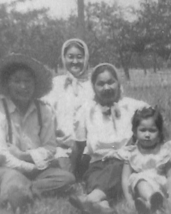 Trois femmes et une jeune fille assises dans l’herbe d’un verger