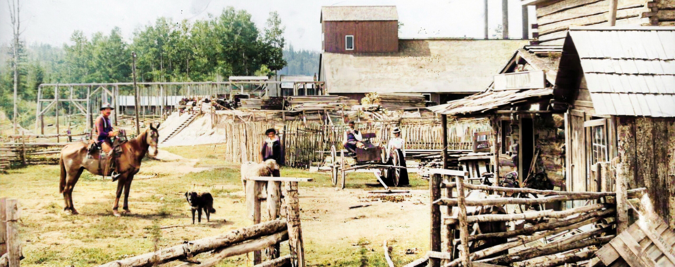 Homme à cheval, chien et charrette devant bâtiments et clôtures en bois